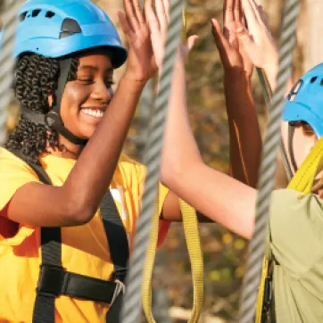 girl high fiving friend on ropes course