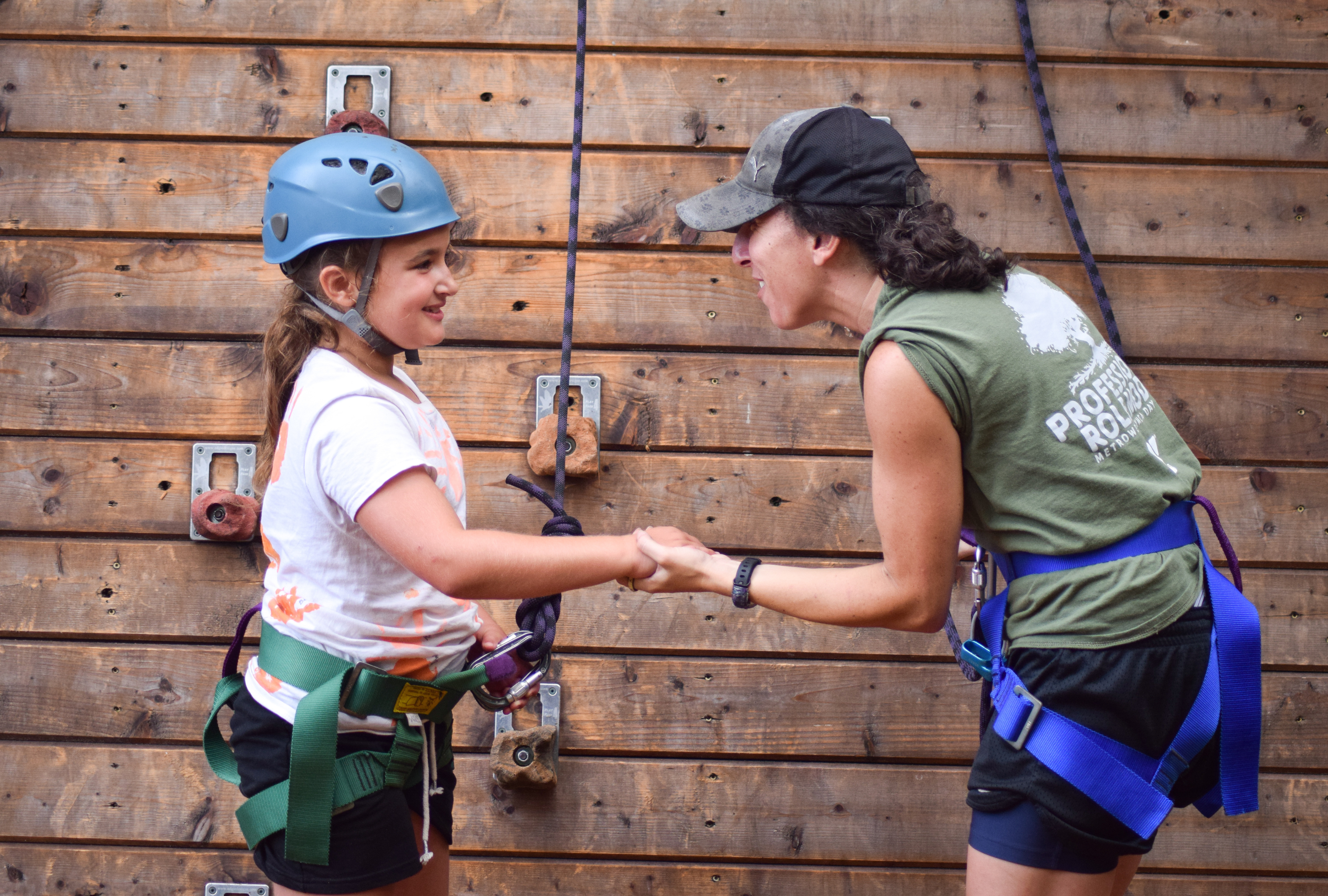 Girl gets encouragement from counselor to climb the rock wall