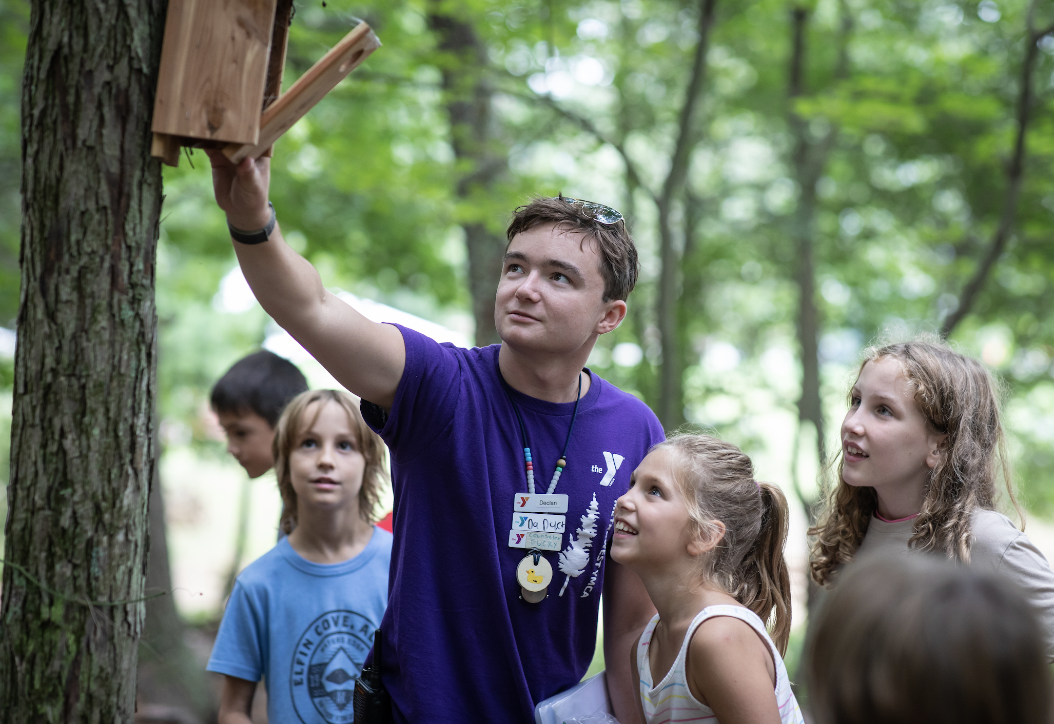 camp counselor shows birdhouse to campers