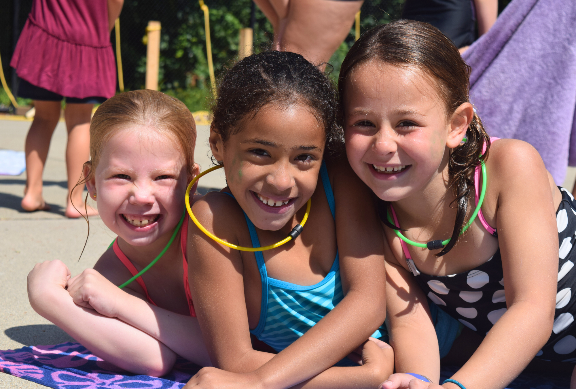 Three girls smile by the pool at Camp Clearbrook