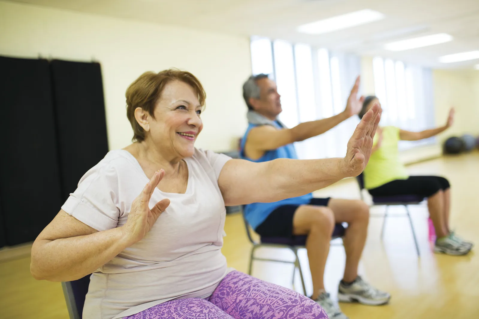 senior citizens smiling and exercising while seated