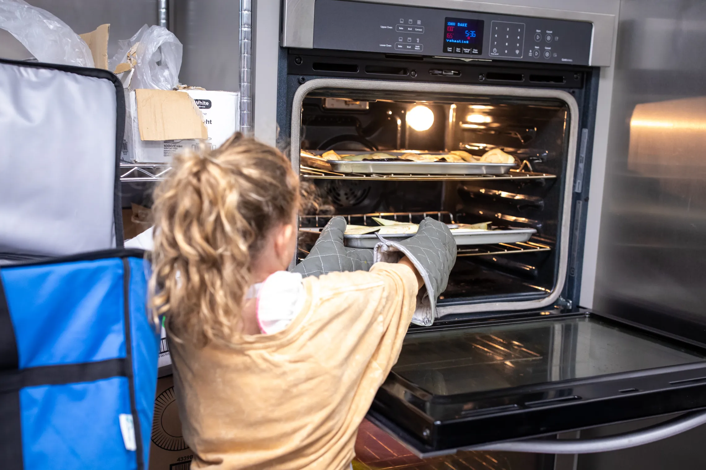 girl putting food into an oven