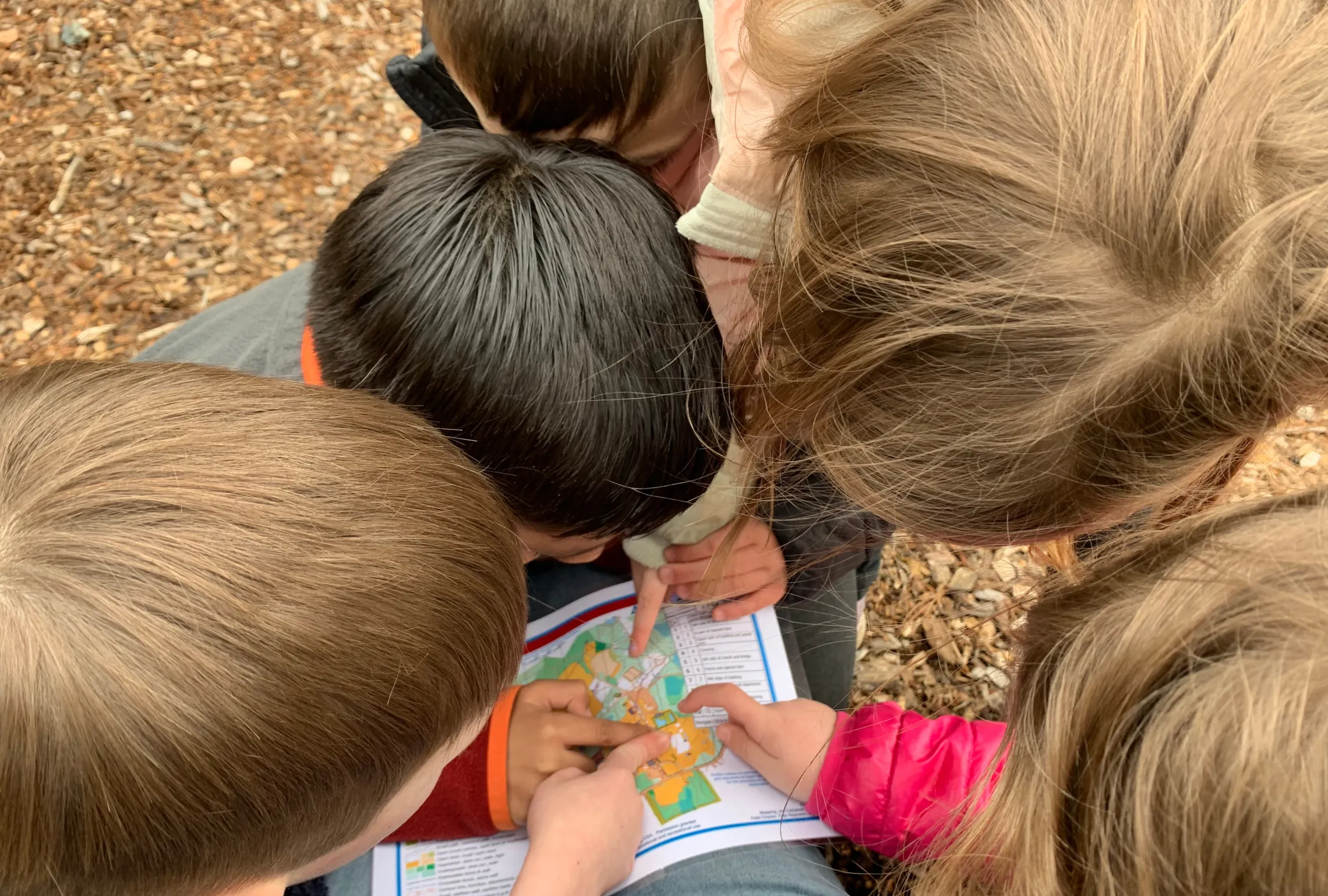 group of kids huddled around a map