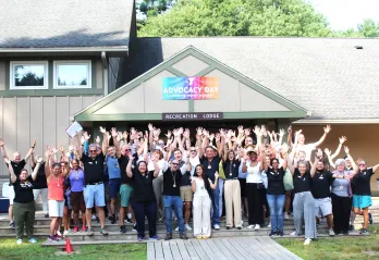 large group of people posing for photo with their arms in the air