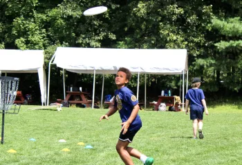 image of boy running to catch a frisbee while playing disc golf