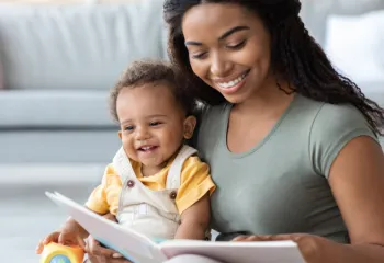 young woman sitting with baby reading a book