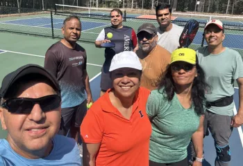selfie of a group of pickleball players standing on an outdoor court