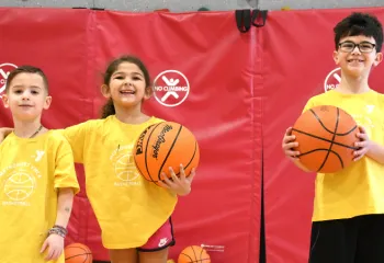 three young kids holding basketballs