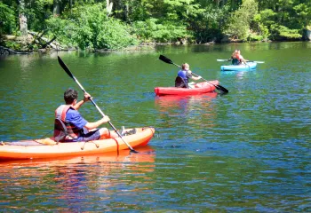 three individuals kayaking on a reservoir on a sunny day