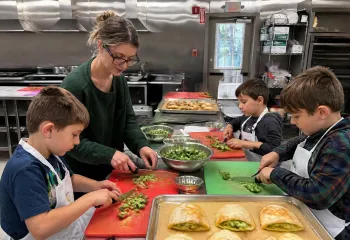 Kids cutting broccoli in the MetroWest YMCA kitchen for cheese pizza pockets