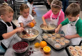 kids preparing cranberry and orange muffins in the MetroWest YMCA kitchen
