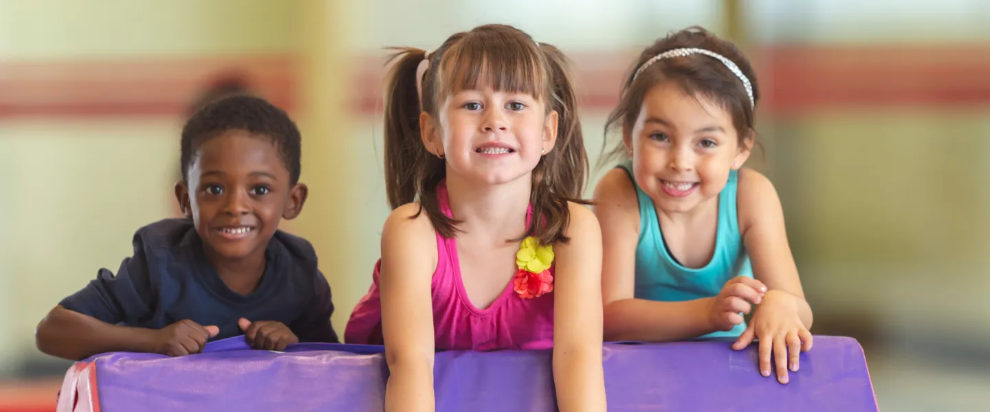 three young kids smiling on obstacle course