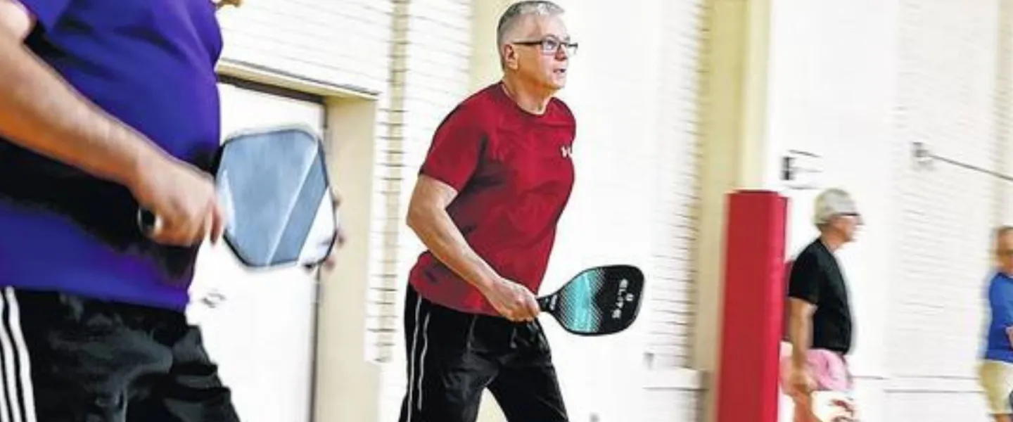 close up of older male playing pickleball at an indoor court