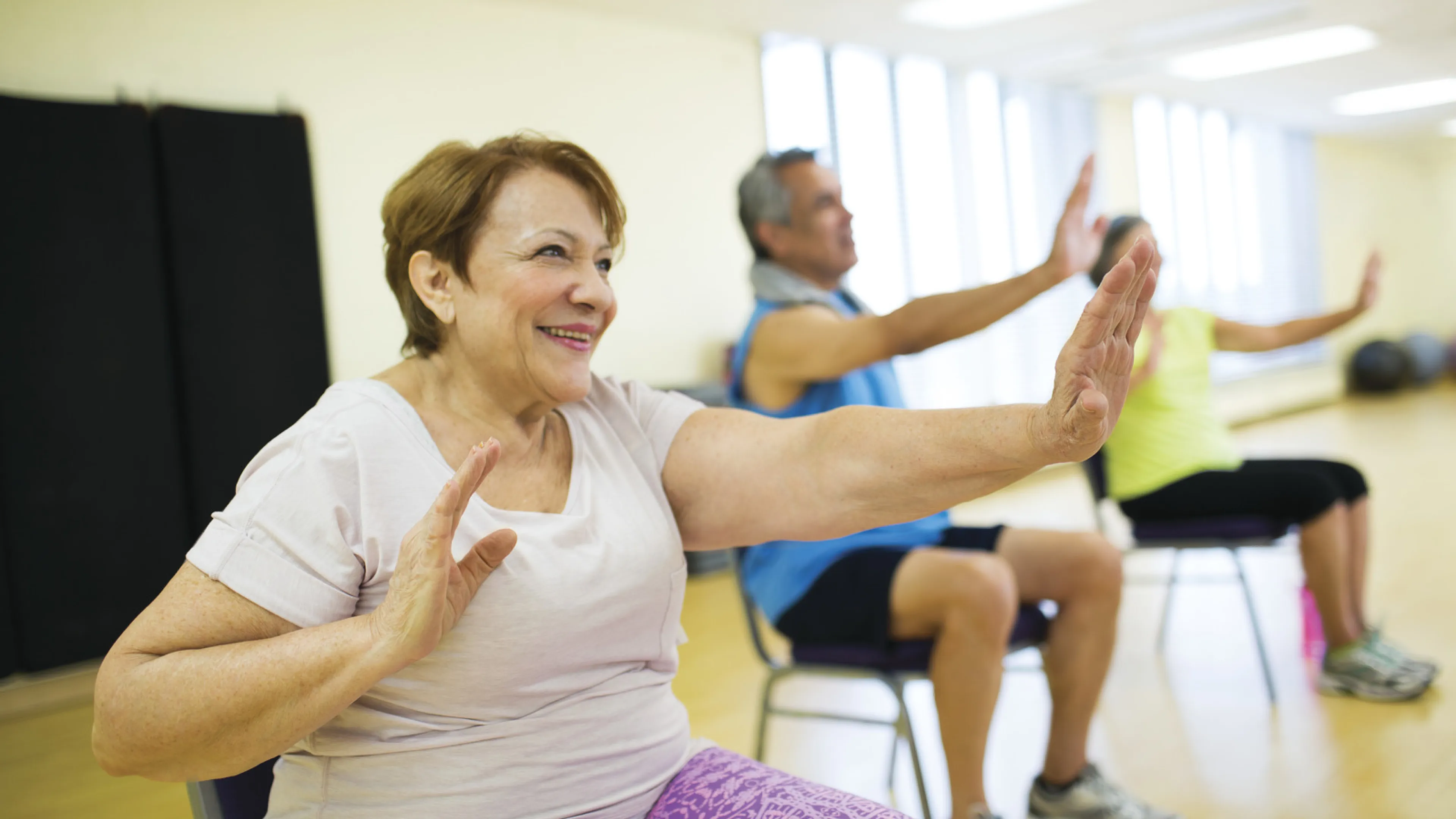 senior citizens smiling and exercising while seated
