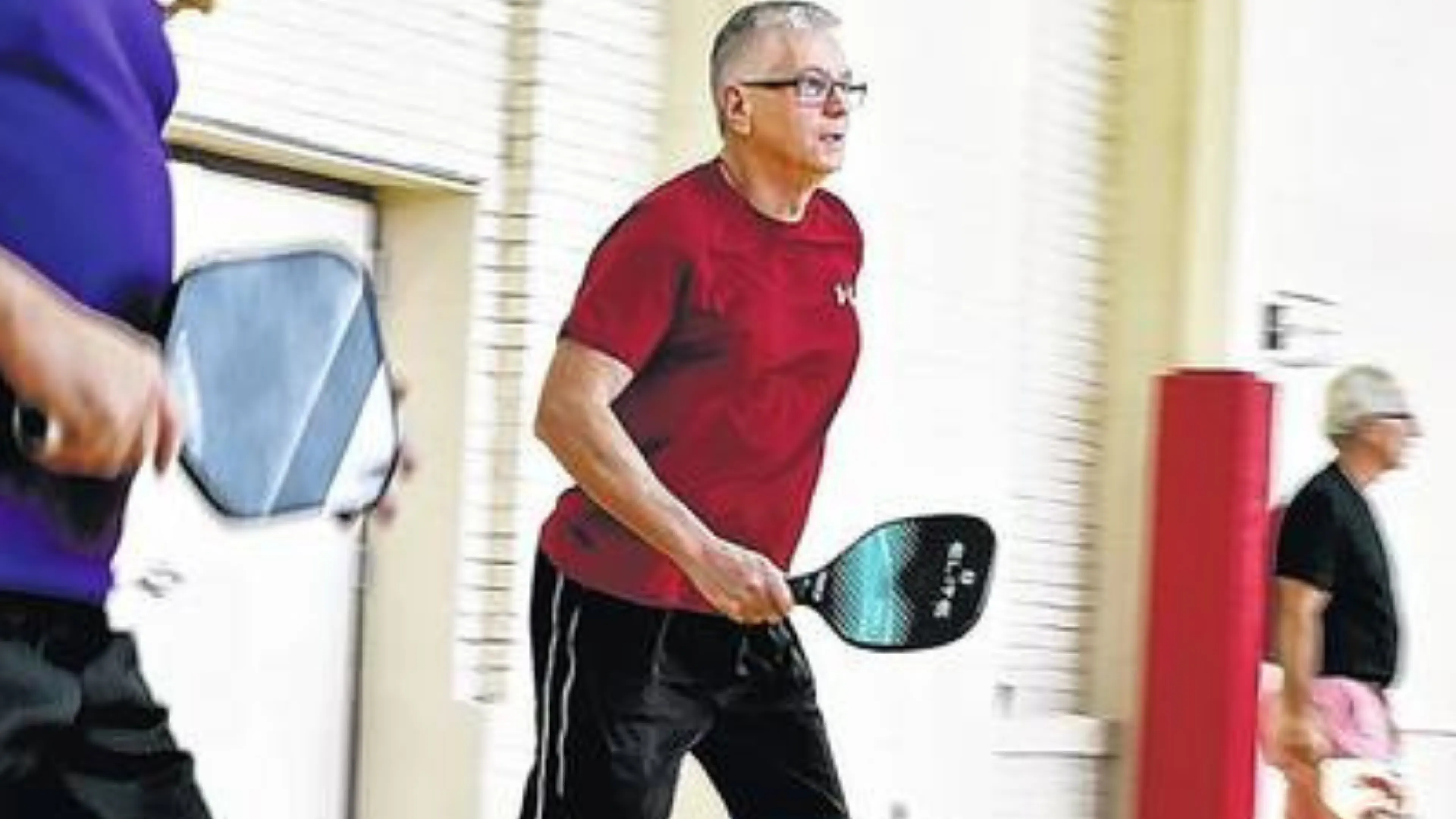close up of older male playing pickleball at an indoor court