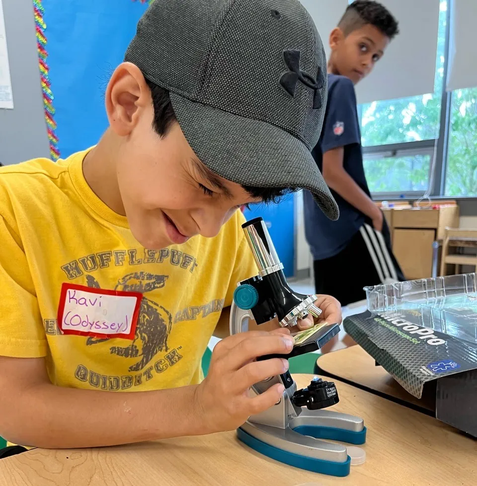 young boy looking through a microscope