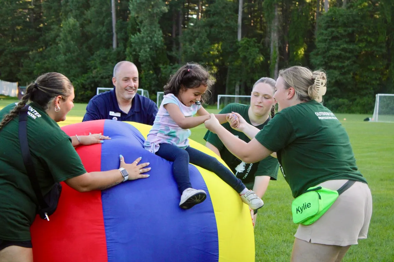 image of camp staff helping young girl 