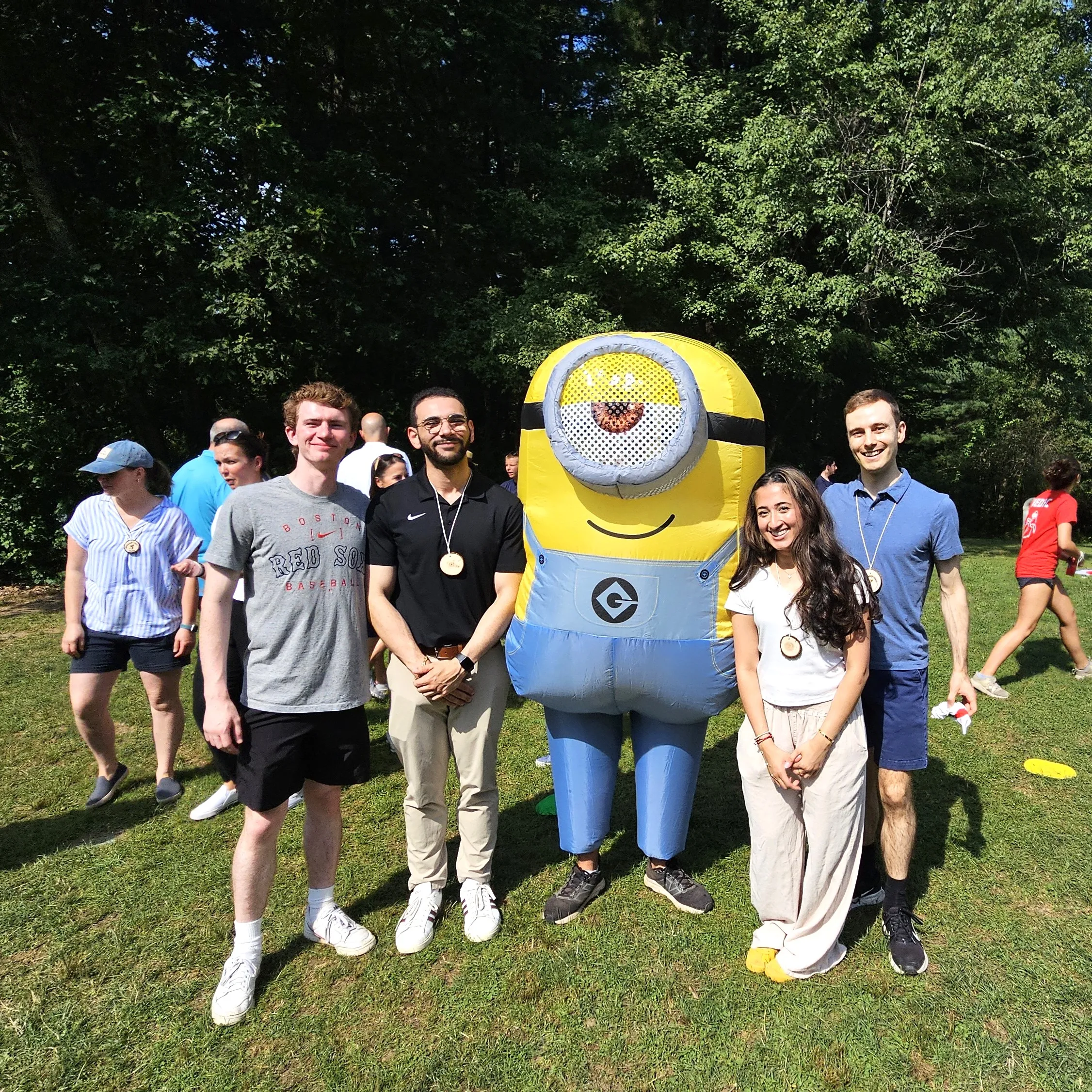 four people posing for photo with a Minion