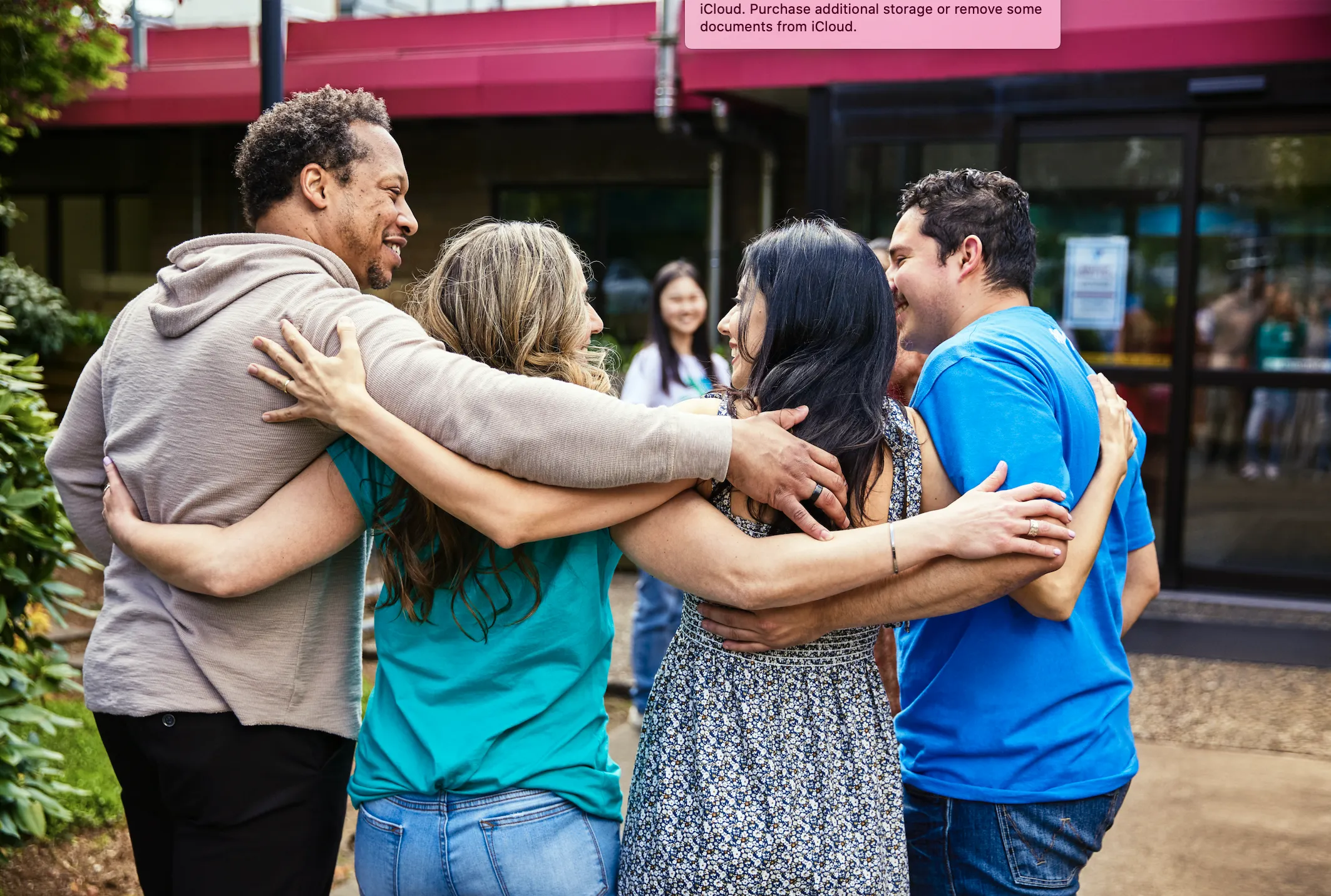 four people standing with their arms around each other