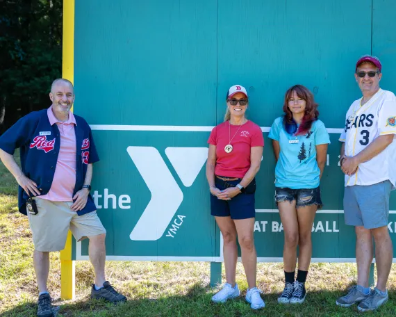 MetroWest YMCA Leadership posing by the Outdoor Center's new Green Monster
