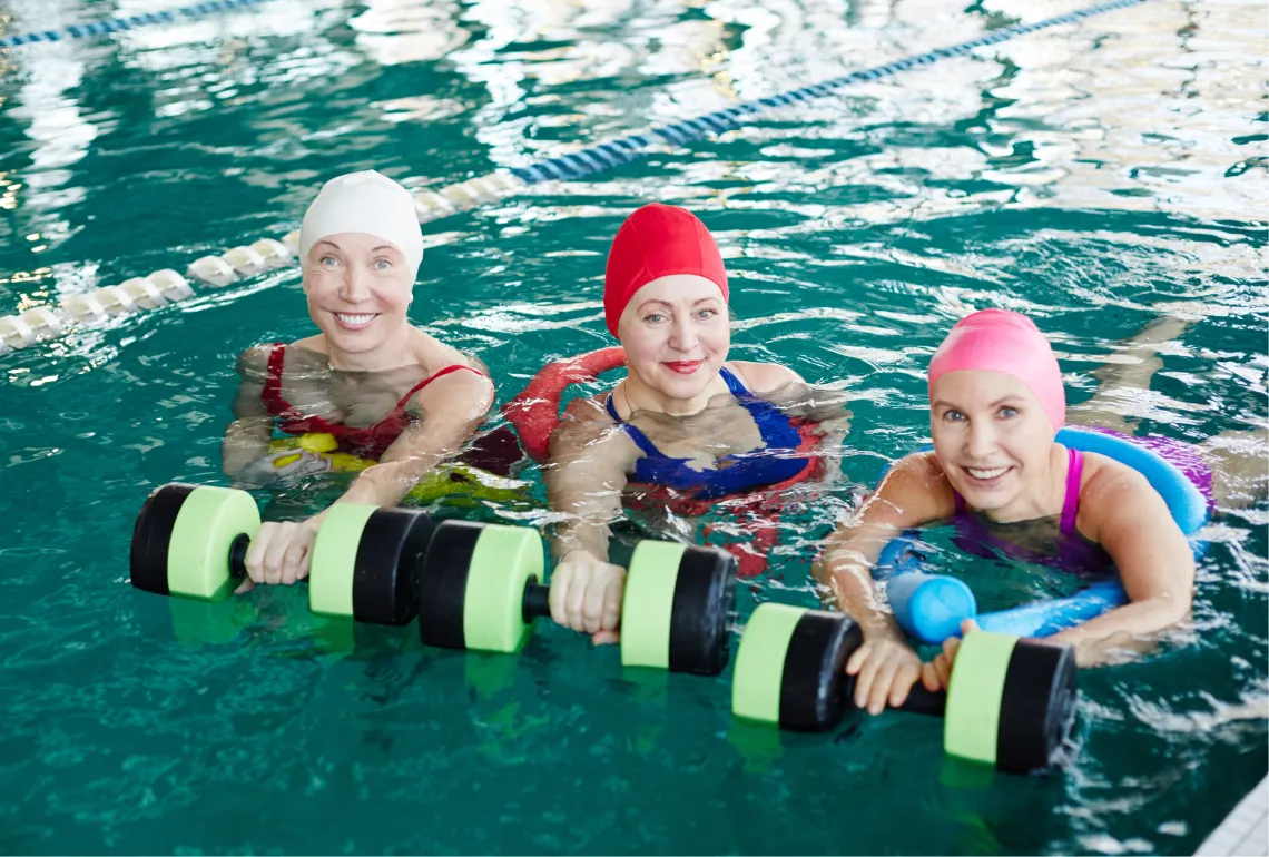 three women in the pool with water weights