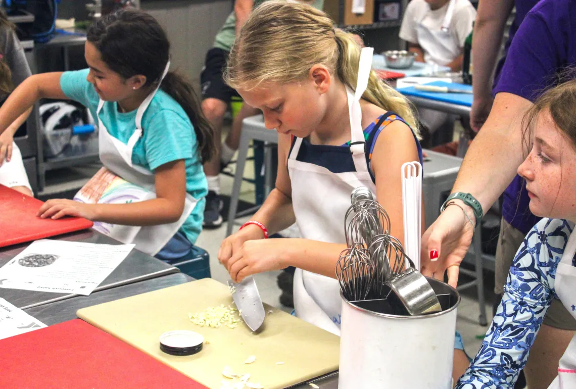 young girl in cooking class chopping garlic