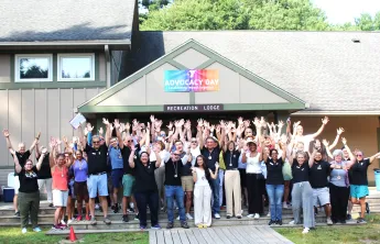 large group of people posing for photo with their arms in the air