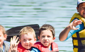 image of young kids waving from a canoe