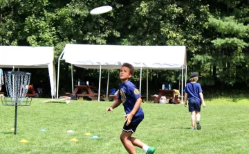 image of boy running to catch a frisbee while playing disc golf