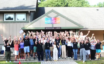 large group of people posing for photo with their arms in the air