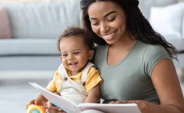 young woman sitting with baby reading a book
