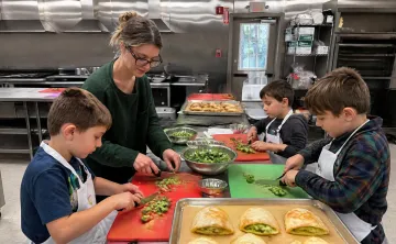 Kids cutting broccoli in the MetroWest YMCA kitchen for cheese pizza pockets