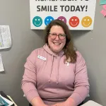 female Y staff member sitting at her desk and smiling