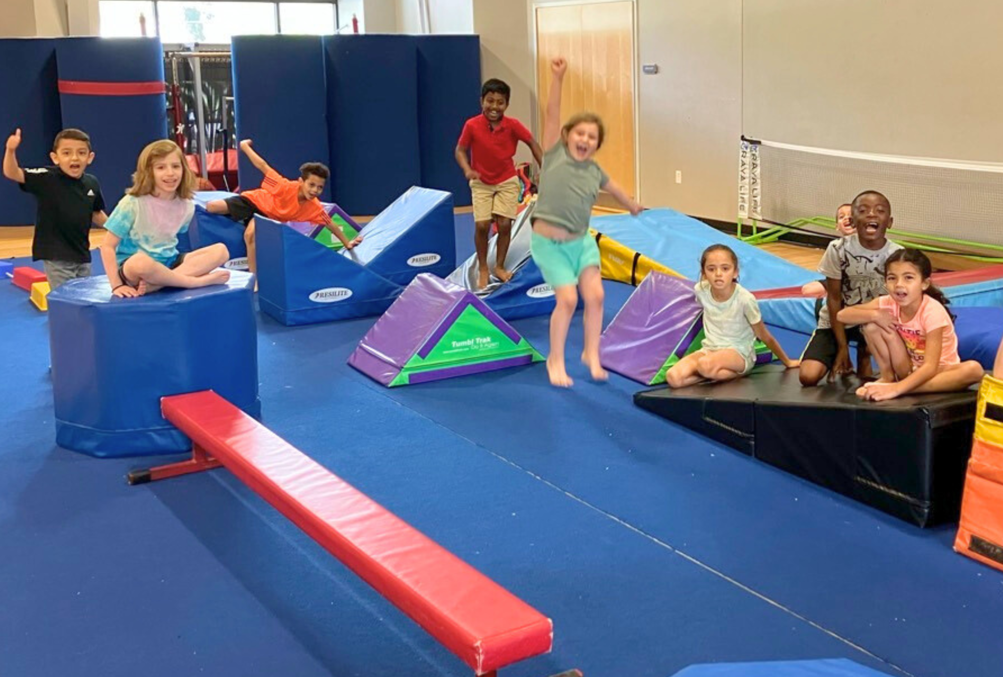Campers pose on the ninja course in the gym